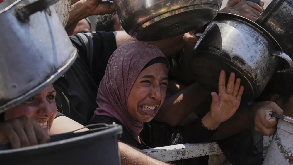 Palestinians struggle to get donated food at a community kitchen, in Gaza City, northern Gaza Strip, Saturday, July 26, 2025. (AP Photo/Abdel Kareem Hana)