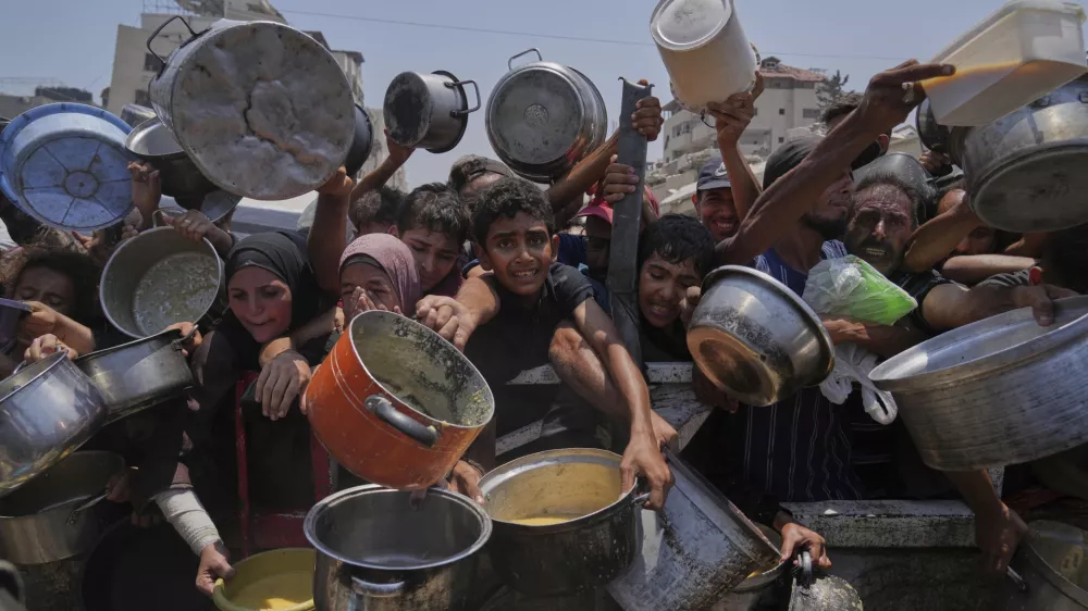 Palestinians struggle to get donated food at a community kitchen, in Gaza City, northern Gaza Strip, Saturday, July 26, 2025. (AP Photo/Abdel Kareem Hana)