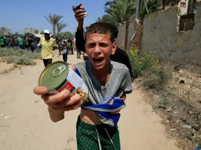 A Palestinian youth holds a can of chickpeas from an aid package dropped from an airplane, amid a hunger crisis, in Zawayda, in the central Gaza Strip, July 28, 2025. REUTERS/Hatem Khaled