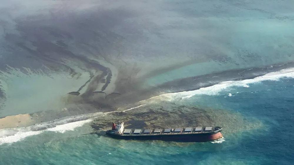 ﻿This photo taken and provided by Eric Villars shows oil leaking from the MV Wakashio, a bulk carrier ship that recently ran aground off the southeast coast of Mauritius, Friday, Aug. 7, 2020. Anxious residents of the Indian Ocean island nation of Mauritius are stuffing fabric sacks with sugar cane leaves to create makeshift oil spill barriers as tons of fuel leak from a grounded ship. The government has declared an environmental emergency and France says it is sending help from its nearby Reunion island. (Eric Villars via AP)