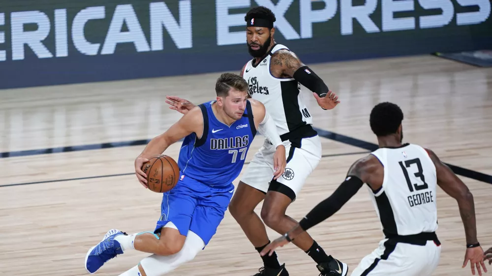 ﻿Aug 21, 2020; Lake Buena Vista, Florida, USA; Dallas Mavericks' Luka Doncic (77) drives against Los Angeles Clippers' Marcus Morris Sr., center, and Paul George (13) during the second half in a NBA basketball first round playoff game at AdventHealth Arena. Mandatory Credit: Ashley Landis/Pool Photo-USA TODAY Sports