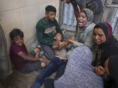 People mourn over the body of a young Palestinian killed while trying to reach trucks carrying humanitarian aid en route to Gaza City, outside the Hamad Al-Qatari Hospital in Beit Lahiya, northern Gaza Strip, Friday, Aug. 1, 2025. (AP Photo/Jehad Alshrafi)