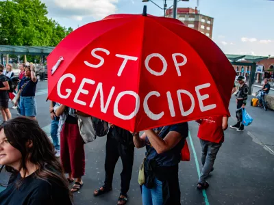 24 July 2025, Netherlands, Nijmegen: A protester holds a red umbrella with the message "Stop the genocide" during a pro-Palestine rally. Outside the train station, people gathered and made loud noises with pots and instruments to call for an end to the famine in Gaza. Photo: Ana Fernandez/SOPA Images via ZUMA Press Wire/dpa