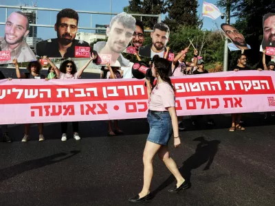 Protesters hold cutout pictures of hostages and a banner that reads "Abandoning the hostages = Destruction of the third temple. All of them in a deal. Pull out of Gaza", as they block a road during a demonstration demanding the immediate end of the war and the release of all hostages who were kidnapped during the deadly October 7, 2023 attack on Israel by Hamas, in Tel Aviv, Israel August 3, 2025. REUTERS/Nir Elias