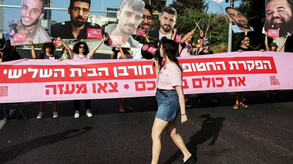 Protesters hold cutout pictures of hostages and a banner that reads "Abandoning the hostages = Destruction of the third temple. All of them in a deal. Pull out of Gaza", as they block a road during a demonstration demanding the immediate end of the war and the release of all hostages who were kidnapped during the deadly October 7, 2023 attack on Israel by Hamas, in Tel Aviv, Israel August 3, 2025. REUTERS/Nir Elias