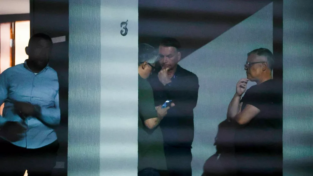 Brazil's former President Jair Bolsonaro talks to unidenfied people at his home after Brazil's Supreme Court put him under house arrest ahead of his trial for an alleged coup plot, in Brasilia, Brazil August 4, 2025. Pedro Ladeira/Folhapress via REUTERS ATTENTION EDITORS – THIS IMAGE HAS BEEN SUPPLIED BY A THIRD PARTY. NO RESALES. NO ARCHIVES. BRAZIL OUT. NO COMMERCIAL OR EDITORIAL SALES IN BRAZIL   TPX IMAGES OF THE DAY