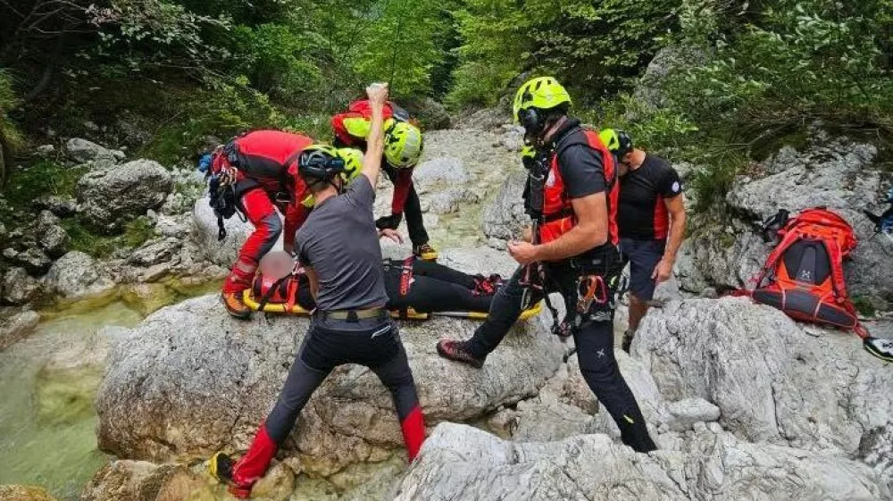 Gorski reševalci iz Bovca pomagajo ponesrečenki pri raftingu. 