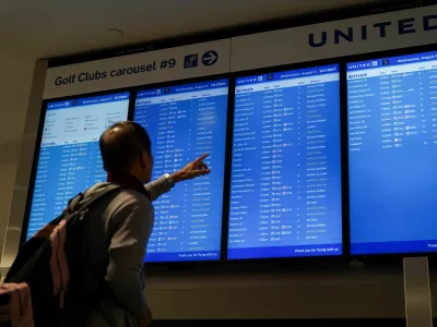Travelers look upon a flight-arrival screen after United Airlines grounded flights due to a tech outage at Newark Liberty International Airport in Newark, New Jersey, U.S., August 6, 2025. REUTERS/Ryan Murphy