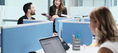 Teamwork with colleagues working and talking in modern office. Busy girl, man and woman at work in coworking space and meeting as co-workers. Business people, worker, job and profession