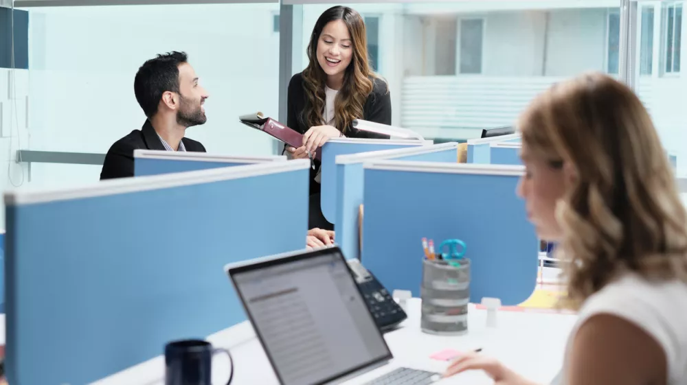 Teamwork with colleagues working and talking in modern office. Busy girl, man and woman at work in coworking space and meeting as co-workers. Business people, worker, job and profession