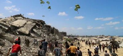 Palestinians run towards parachutes carrying aid packages airdropped over northern Gaza Strip, August 7, 2025. REUTERS/Ebrahim Hajjaj