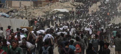 FILED - 01 August 2025, Palestinian Territories, Jabalia: Palestinians carry sacks of flour they collected from a humanitarian aid convoy, as they make their way along a destroyed road in Jabalia. Against the backdrop of a looming hunger crisis in the Gaza Strip, large-scale aid deliveries reached the besieged and embattled coastal area for the first time in months on Sunday. Photo: Omar Ashtawy/APA Images via ZUMA Press Wire/dpa