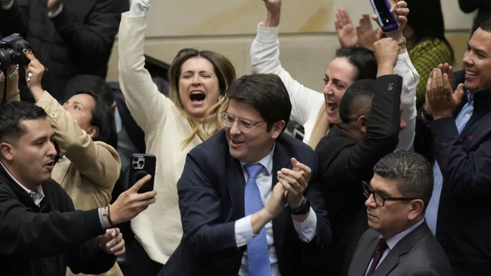 FILE - Miguel Uribe Turbay, center in blue tie, a Colombian senator and presidential candidate for the right-wing Centro Democrático party, celebrates after voting against a labor reform referendum proposed by the government, in Bogota, Colombia, May 14, 2025. (AP Photo/Fernando Vergara, File)