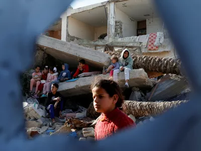 Palestinian children sit on rubble as they wait to receive food cooked by a charity kitchen, during the Muslim holy month of Ramadan, in Rafah, in the southern Gaza Strip, March 13, 2025. REUTERS/Hatem Khaled