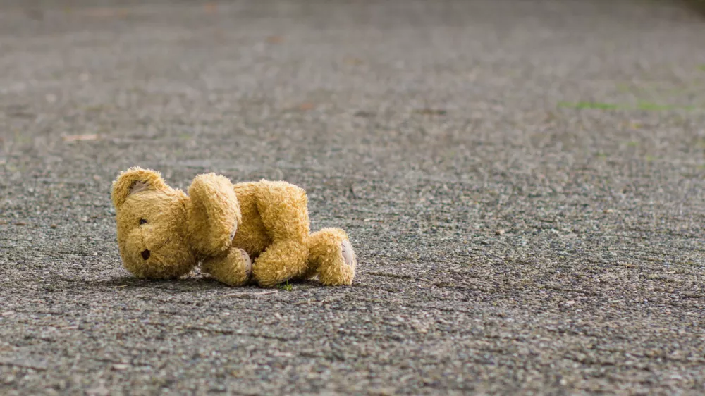 ﻿Teddy bear lies on the road