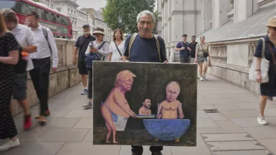 Satirical artist Kaya Mar, displays his latest painting depicting President Trump, Russian President Putin and Ukraine's President Zelenskyy, outside Downing Street, in London, Wednesday, Aug. 13, 2025. (AP Photo/Joanna Chan)