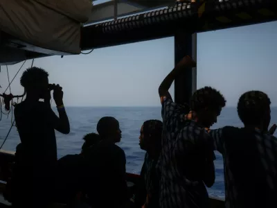 A young migrant looks for land through binoculars, aboard the migrant search and rescue ship Sea-Watch 5, operated by German NGO Sea-Watch, as the ship makes its way towards the designated port of Salerno, Italy, August 13, 2025. REUTERS/Louisa Gouliamaki