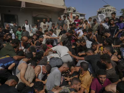 Palestinians struggle to collect humanitarian aid airdropped by parachutes into Gaza City, northern Gaza Strip, Thursday, Aug. 14, 2025. (AP Photo/Jehad Alshrafi)