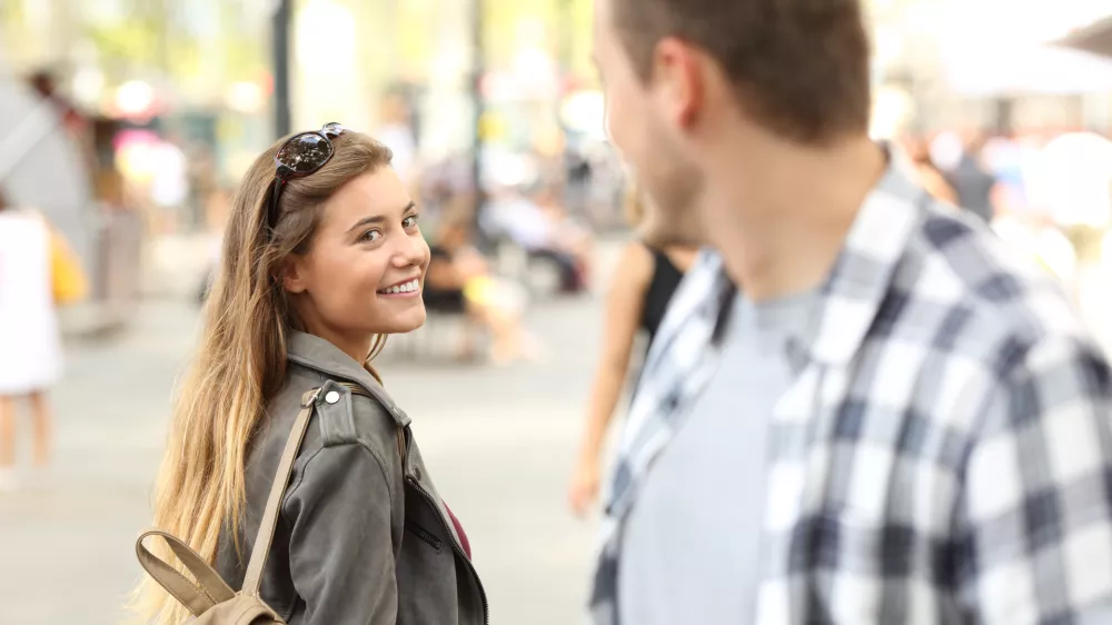 Strangers girl and guy flirting looking each other on the street / Foto: Antonioguillem