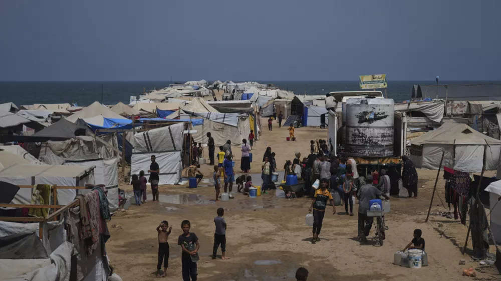 Displaced Palestinians gather to collect water from a truck during a heat wave at a makeshift tent camp in Khan Younis, Gaza Strip, Wednesday, Aug. 13, 2025. (AP Photo/Abdel Kareem Hana)