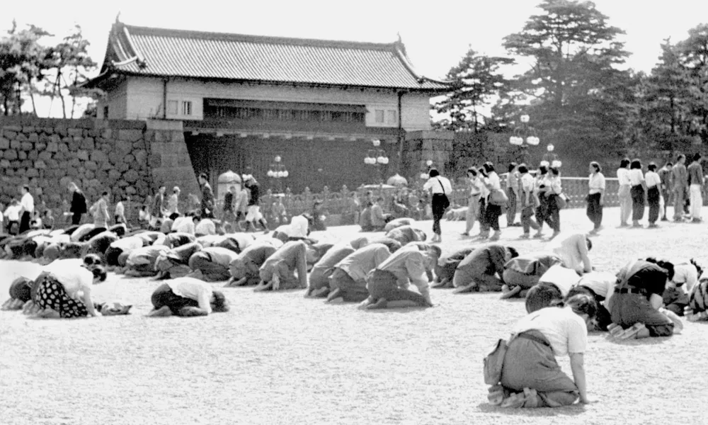 FILE - Japanese people kneel in front of the Imperial Palace in Tokyo as Emperor Hirohito announced on radio that Japan was defeated in the World War II, on Aug. 15, 1945. (Kyodo New via AP, File)