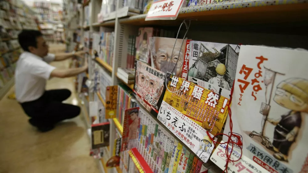A Japanese Manga "Ichi Efu" (2nd R), which centres on workers at the Fukushima Daiichi nuclear plant, is seen on a bookshelf as a staff adjusts manga comics at a bookstore in Tokyo June 23, 2014. Japanese farmers in Fukushima try to convince sceptical visitors that their crops are safe from radiation. Blood trickles from the nose of a reporter who visits the area. These are just two of the tales from the aftermath of the world's worst nuclear disaster in 25 years - as told by manga, Japan's ubiquitous comics for adults and teens, which have taken up Fukushima on an unprecedented scale even as Japanese film largely avoids the topic. Picture taken June 23, 2014. REUTERS/Yuya Shino (JAPAN - Tags: SOCIETY DISASTER) / Foto: Yuya Shino