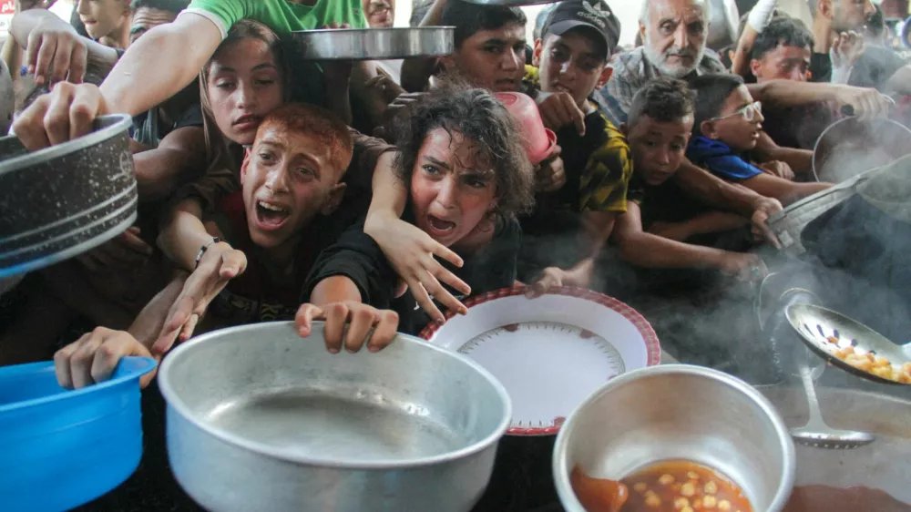 FILE PHOTO: Palestinians gather to receive food cooked by a charity kitchen, amid the Israel-Hamas conflict, in the northern Gaza Strip, September 11, 2024. REUTERS/Mahmoud Issa/File Photo