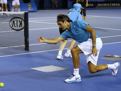 Switzerland's Roger Federer throws the ball along the court as he acts as a ball boy during an exhibition match during the Kids Tennis Day at Melbourne Park ahead of the Australian Open tennis championship in Melbourne, Australia, Saturday, Jan. 12, 2013. (AP Photo/Andy Wong)