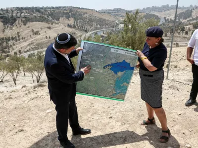 FILE PHOTO: Israeli Finance Minister Bezalel Smotrich and a woman hold a map that shows the long-frozen E1 settlement scheme, that would split East Jerusalem from the occupied West Bank, on the day of a press conference near the Israeli settlement of Maale Adumim, in the Israeli-occupied West Bank, August 14, 2025. REUTERS/Ronen Zvulun/File Photo