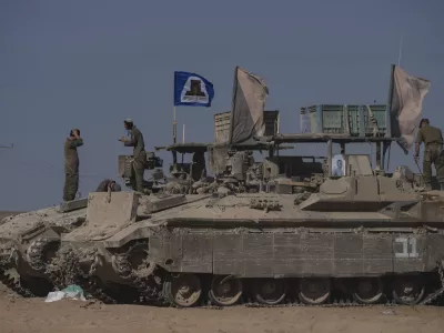 Israeli soldiers stand on the top of armoured vehicles parked on an area near the Israeli-Gaza border, as seen from southern Israel, Wednesday, Aug. 20, 2025. (AP Photo/Maya Levin)