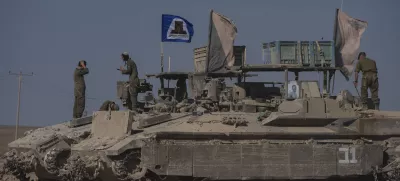 Israeli soldiers stand on the top of armoured vehicles parked on an area near the Israeli-Gaza border, as seen from southern Israel, Wednesday, Aug. 20, 2025. (AP Photo/Maya Levin)