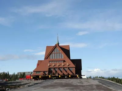 Workers stand in front of Kiruna's old wooden church on its final destination after a two-day relocation trip to a new site next to a cemetery, to save its wooden walls from ground subsidence and the expansion of the world's largest underground iron ore mine, in Kiruna, Sweden August 20, 2025. REUTERS/Leonhard Foeger