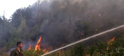 A fire fighter sprays water over a forest fire near the village of Dubovo, some 240 km (150 miles) east of Sofia, July 27, 2007. A heatwave that has roasted much of the Balkans for a week abated in the north on Wednesday but sizzled on in Greece and left scores of wildfires throughout the region. REUTERS/ Nikolay Doychinov (BULGARIA)