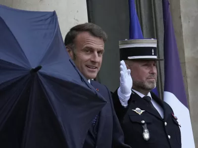 French President Emmanuel Macron uses an umbrella as he waits for Lebanese Prime Minister Nawaf Salam Thursday, July 24, 2025 at the Elysee Palace in Paris. (AP Photo/Michel Euler)