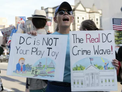 A demonstrator protest against President Donald Trump's use of federal law enforcement and National Guard troops in the city during a rally along the U street corridor in northwest Washington, Saturday, Aug. 23, 2025. (AP Photo/Jose Luis Magana)