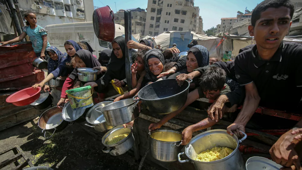 24 August 2025, Palestinian Territories, Gaza: Palestinians wait to receive food from a charity kitchen, amid the on going famine. The United Nations has warned that ''the entire population of Gaza is facing the risk of famine'' since Israel closed border crossings on 02 March 2025, preventing the entry of essential supplies. Photo: Omar Ashtawy/APA Images via ZUMA Press Wire/dpa