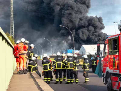 25 August 2025, Hamburg: Emergency services prepare for their deployment to extinguish a major fire in a warehouse in Hamburg. A fire has broken out in a warehouse in the Port of Hamburg, causing a major motorway nearby to be closed. Photo: Bodo Marks/dpa