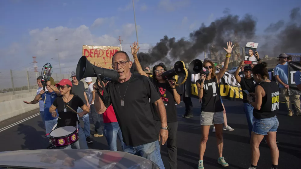 Activists block a highway during a protest demanding the immediate release of hostages held by Hamas and calling for the Israeli government to reverse its decision to take over Gaza City and other areas in the Gaza Strip, near the city of Lod, Israel, Tuesday, Aug. 26, 2025. (AP Photo/Ohad Zwigenberg)
