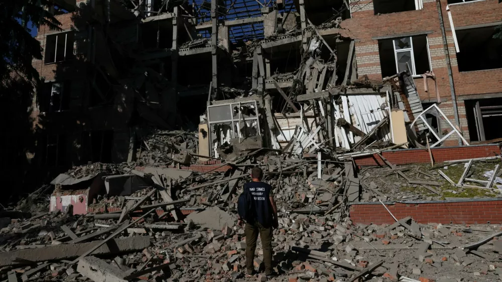 A worker from the war crimes prosecutor's office takes in the damage from overnight shelling that landed on a building of Kharkiv's Housing and Communal College as Russia's attack on Ukraine continues in Kharkiv, Ukraine, June 21, 2022. REUTERS/Leah Millis