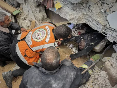 FILE - EDS NOTE: GRAPHIC CONTENT - Rescue workers and volunteers attempt to pull the body of a man from the rubble following an Israeli army airstrike in Khan Younis, southern Gaza Strip, Thursday, March 20, 2025. (AP Photo/Mariam Dagga, File)