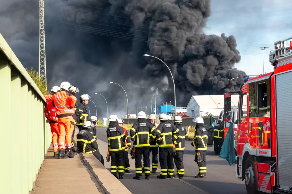 25 August 2025, Hamburg: Emergency services prepare for their deployment to extinguish a major fire in a warehouse in Hamburg. A fire has broken out in a warehouse in the Port of Hamburg, causing a major motorway nearby to be closed. Photo: Bodo Marks/dpa