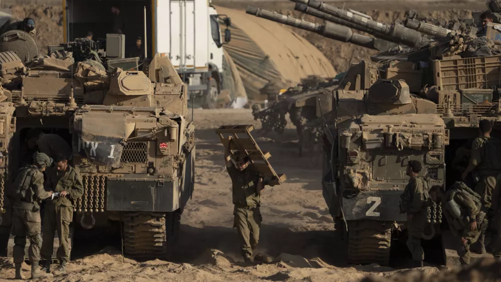 Israeli soldiers work on their armored vehicles parked in a staging area near the Israeli-Gaza border, as seen from southern Israel, Tuesday, Aug. 26, 2025. (AP Photo/Maya Levin)