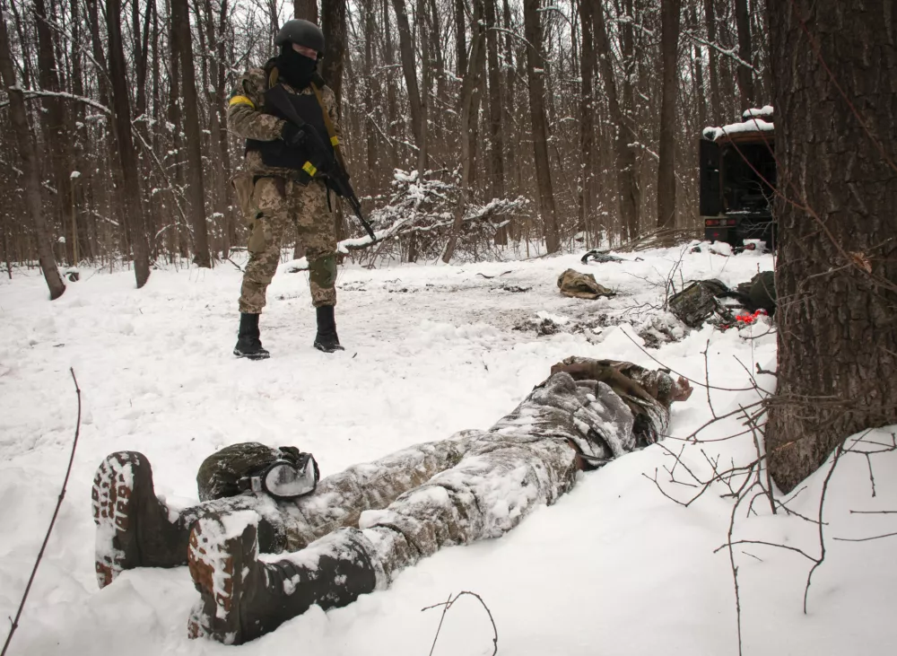﻿A volunteer of the Ukrainian Territorial Defense Forces looks at a dead body of a soldier lying in a forest in the outskirts of Kharkiv, Ukraine's second-largest city, Monday, March 7, 2022. Russia announced yet another cease-fire and a handful of humanitarian corridors to allow civilians to flee Ukraine. Previous such measures have fallen apart and Moscowâ€™s armed forces continued to pummel some Ukrainian cities with rockets Monday. (AP Photo/Andrew Marienko).