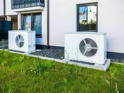 2XWNAMH Two air source heat pumps installed outside of new and modern city house, green renewable energy concept of heat pump