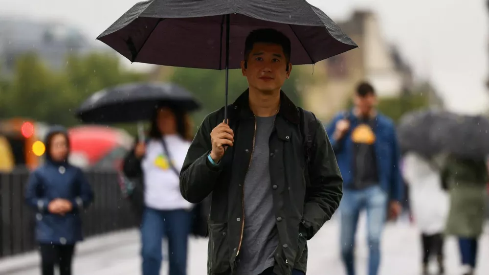 People cross the Westminster Bridge in the rain, in London, Britain, August 29, 2025. REUTERS/Jack Taylor