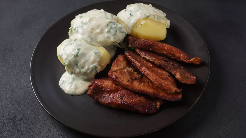 Crispy fried pork with creamy parsley sauce and boiled potato in the plate on the table or stegt flæsk, a classic Danish cuisine. / Foto: Nataly Hanin