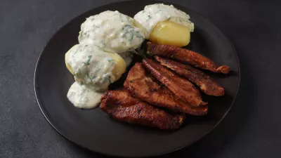 Crispy fried pork with creamy parsley sauce and boiled potato in the plate on the table or stegt flæsk, a classic Danish cuisine. / Foto: Nataly Hanin