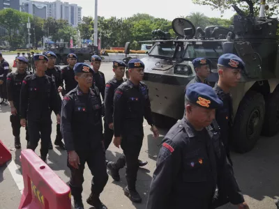 Members of Indonesian police's paramilitary unit Mobile Brigade walk past army armored vehicles parked near the National Monument following days of violent protests against lavish allowances given to parliament members, in Jakarta, Indonesia, Tuesday, Sept. 2, 2025. (AP Photo/Dita Alangkara)