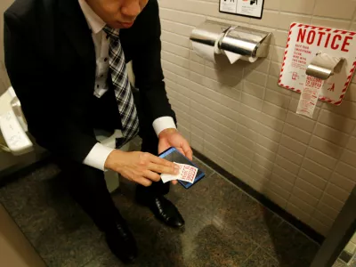 ﻿A man demonstrates a toilet roll for wiping smartphones, installed by Japanese mobile phone company NTT Docomo, in a high-tech bathroom equipped with bidet and heated seat at Narita international airport in Narita, Japan, December 28, 2016. REUTERS/Toru Hanai