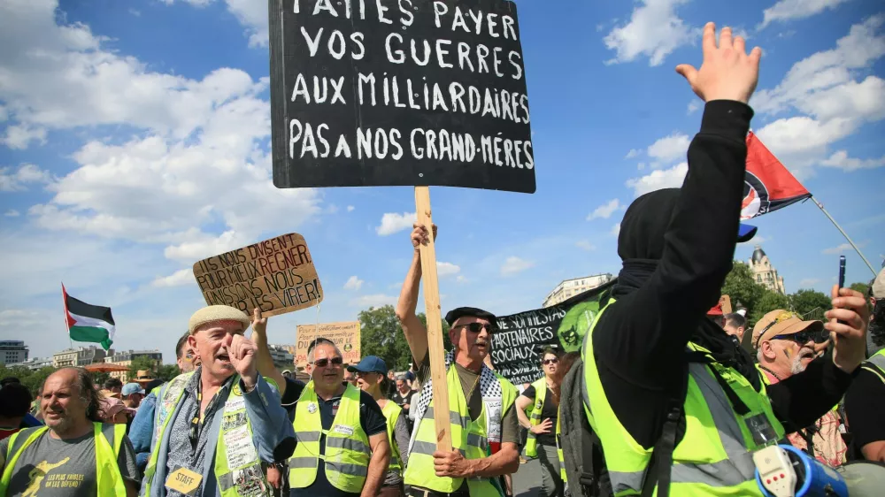 Demonstranti med letošnjimi delavskim praznikom. Na transparentu piše: Za vaše vojne naj plačajo milijarderji, ne naše babice.